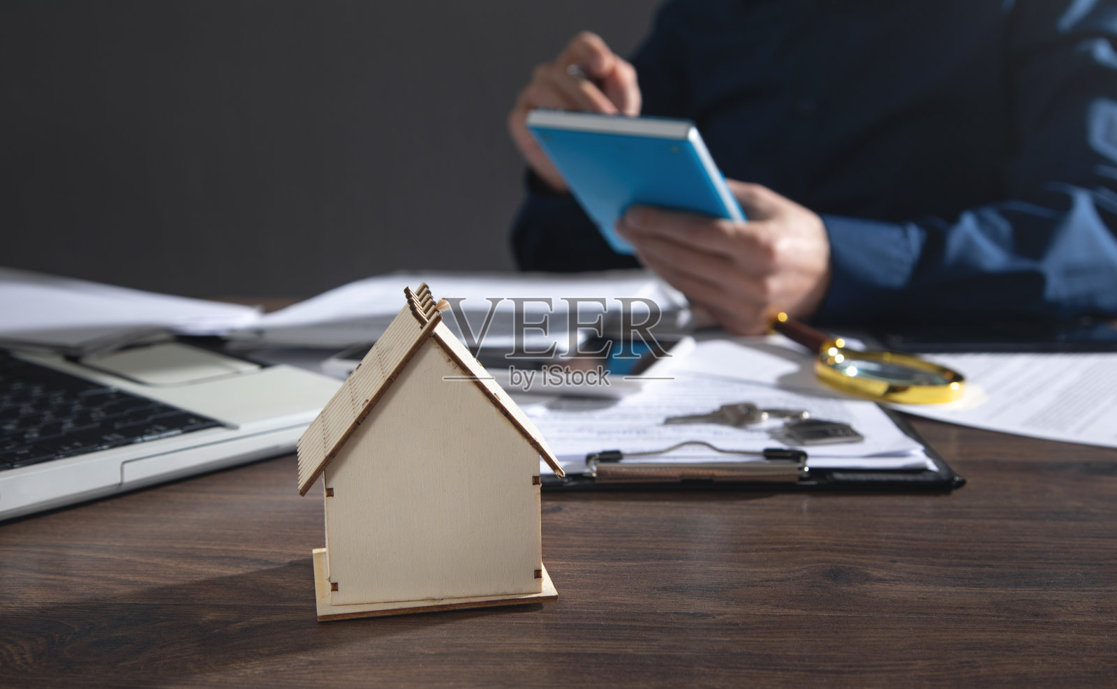 房子模型放在桌子上。在办公室工作的房地产经纪人照片摄影图片