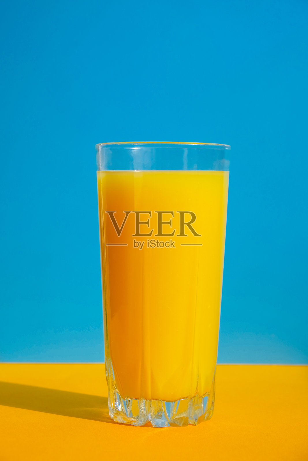 一杯鲜榨橙汁，蓝色和黄色的背景。果汁，新鲜冷饮。点心在夏天照片摄影图片