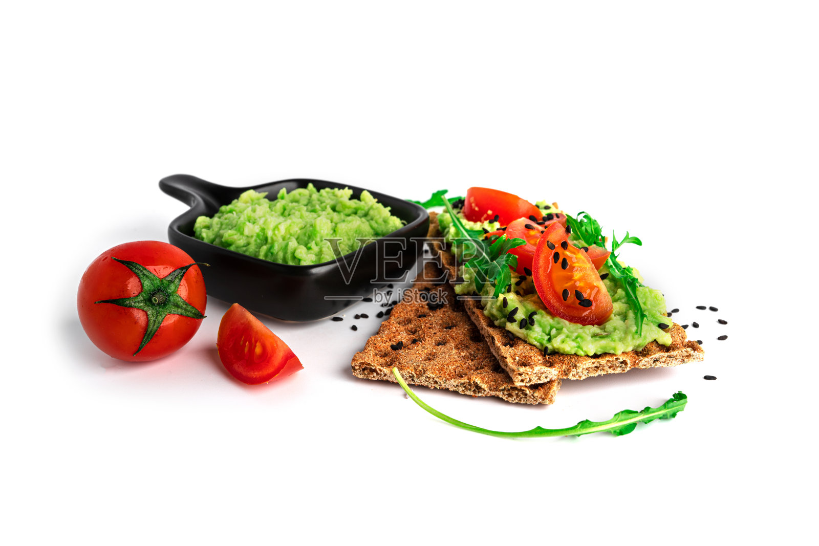 鳄梨三明治配鳄梨奶油和黑麦脆面包当零食。纤维、健身和减肥食品。黑麦面包与鳄梨酱，芝麻菜和圣女果隔离在白色的背景上照片摄影图片