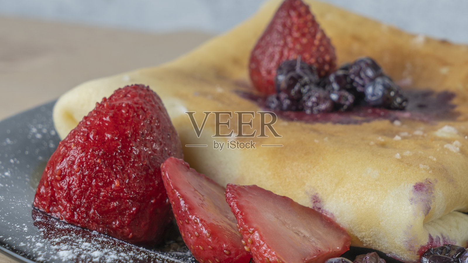 经典的美国煎饼与浆果在黑色的盘子背景。蓝莓草莓可丽饼。照片摄影图片