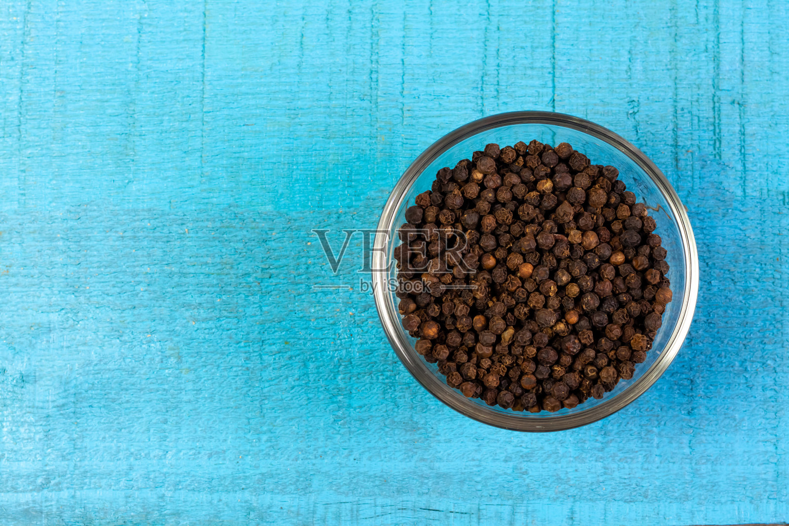 黑胡椒在透明玻璃碗蓝色木制背景。照片摄影图片