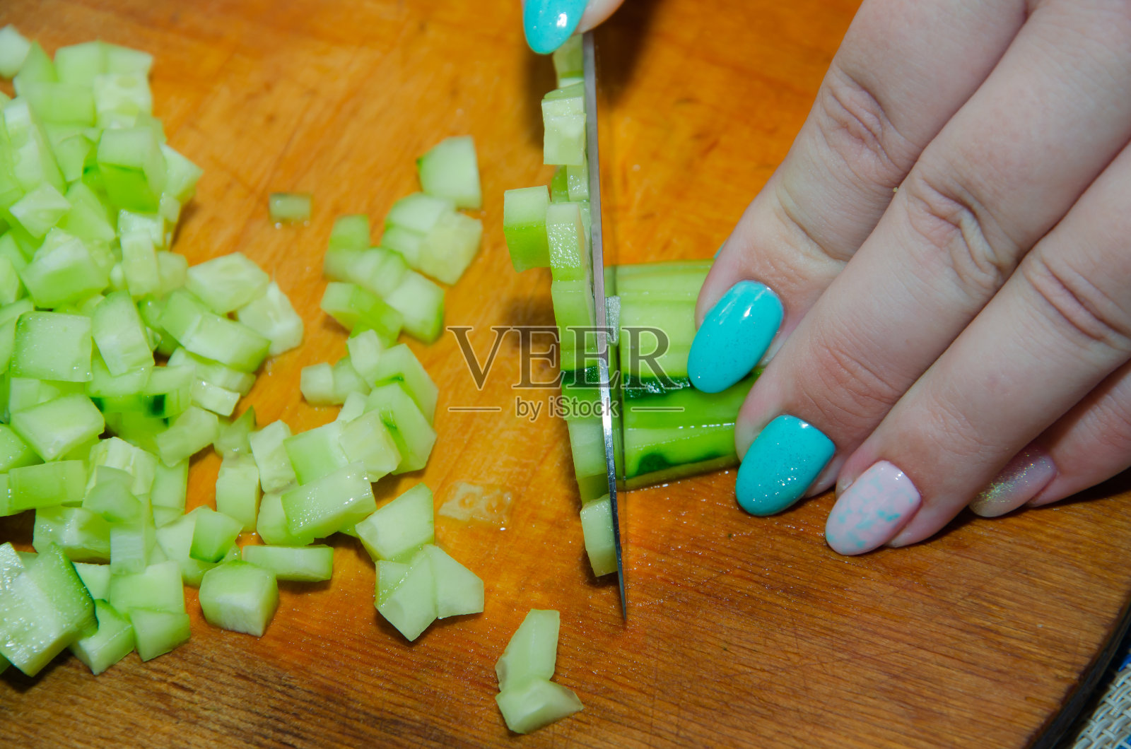 用三德刀切英国黄瓜：在竹制砧板上精细切碎有机无籽黄瓜照片摄影图片