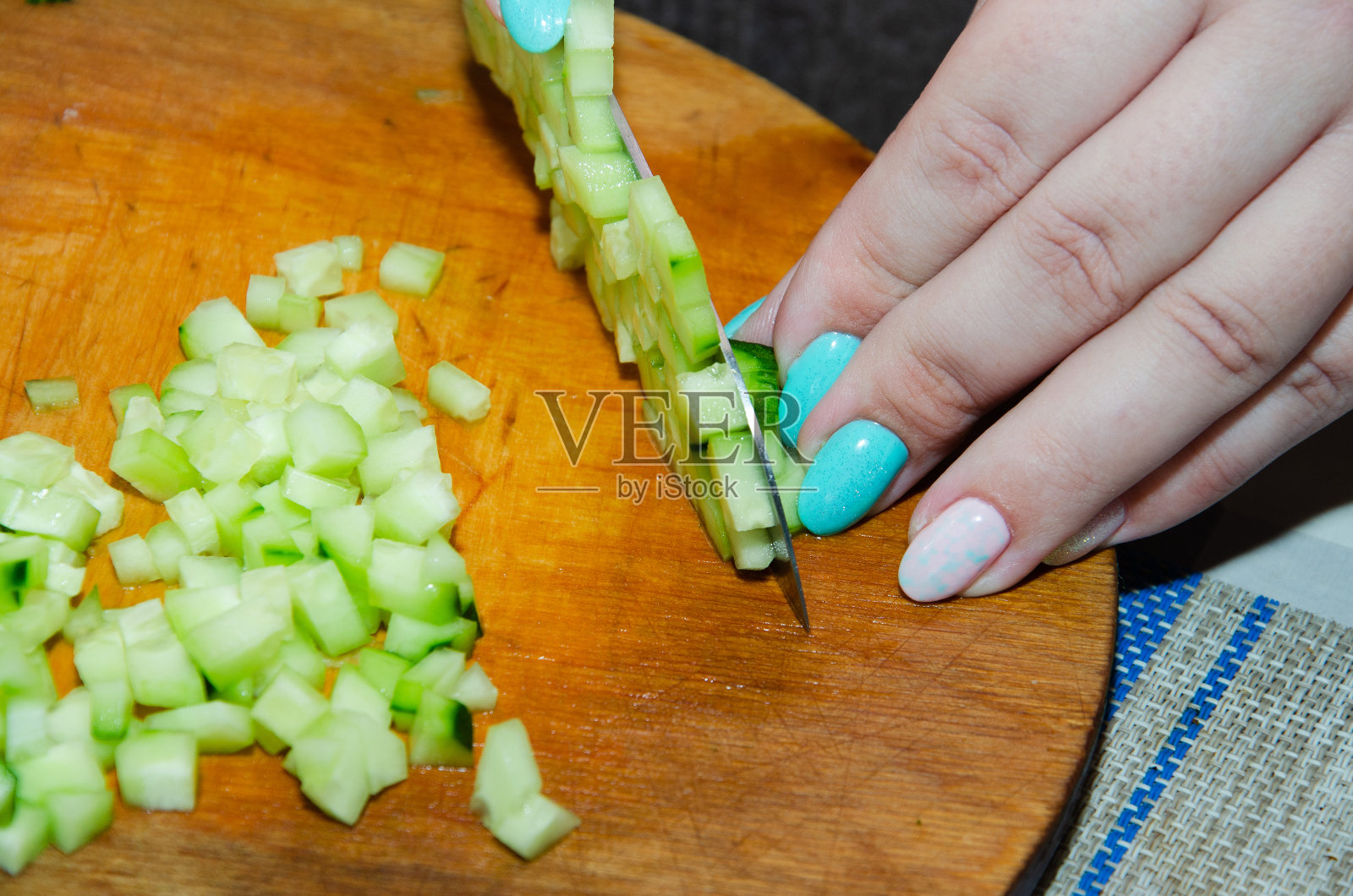 用三德刀切英国黄瓜：在竹制砧板上精细切碎有机无籽黄瓜照片摄影图片