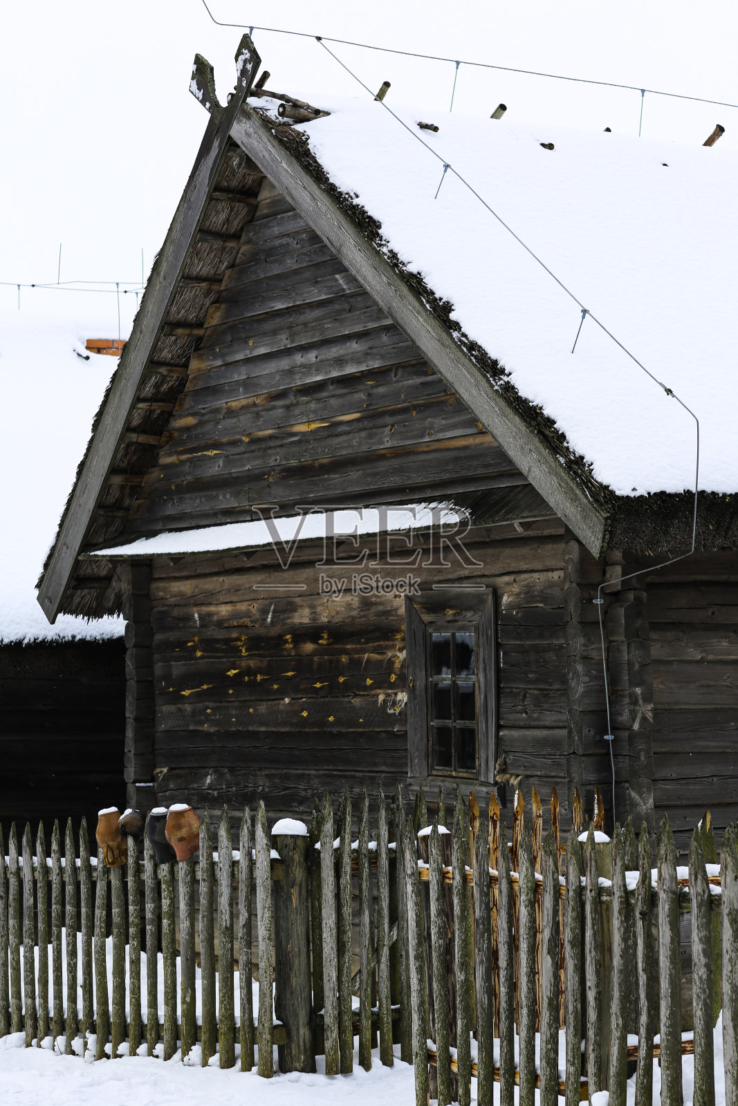 俄罗斯冬天的风景。一间旧木屋，一间茅草屋顶的木屋。被雪覆盖的废弃俄罗斯村庄。木屋，带谷仓，有木制柳条篱笆。照片摄影图片