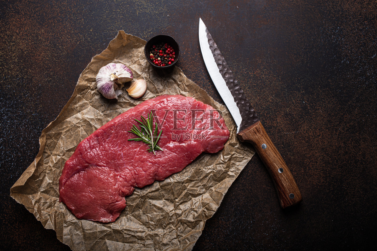 烤纸上放牛扒，配以迷迭香、大蒜和香料照片摄影图片