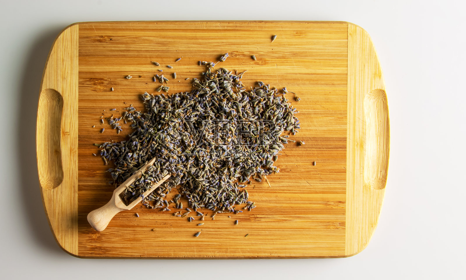薰衣草花为家居和衣柜清新剂，天然防蚊剂。在木制背景的抹刀上放着芳香的干花照片摄影图片