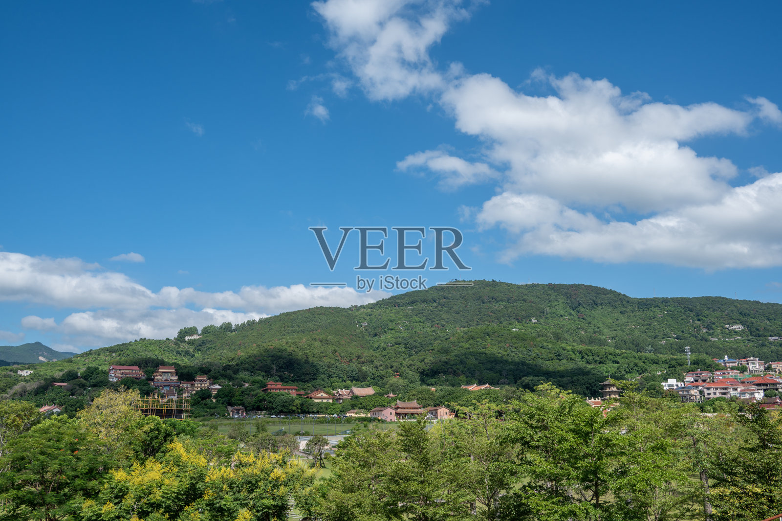 蓝天白云下，村庄在山上。照片摄影图片