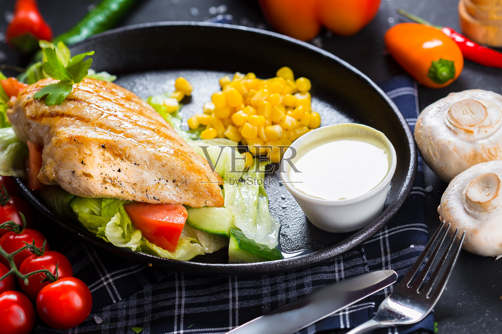 盘子上放着炸鸡胸肉、蔬菜、圣女果、黑色孤立背景的餐具照片摄影图片