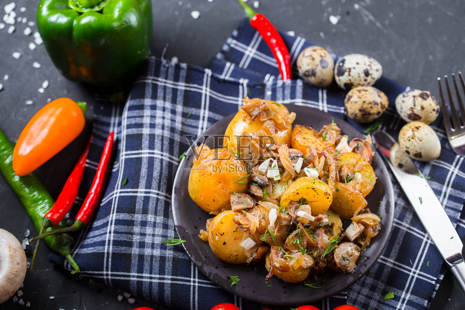 盘子上放着质朴的土豆、洋葱和蘑菇、圣女果、黑色孤立背景的餐具照片摄影图片