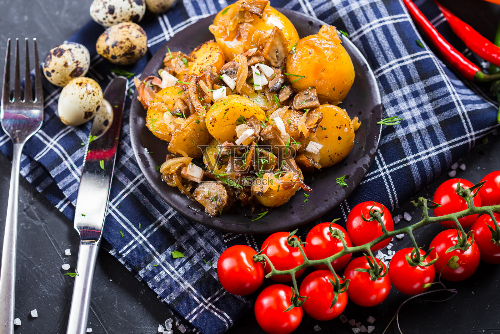 盘子上放着质朴的土豆、洋葱和蘑菇、圣女果、黑色孤立背景的餐具照片摄影图片