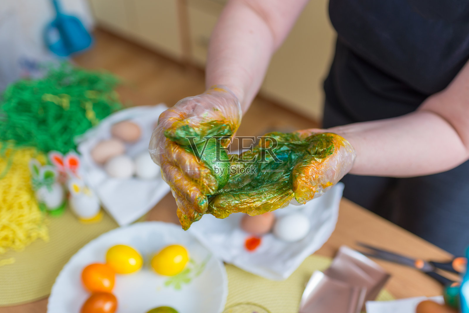 复活节彩蛋绘画。女人在家里的厨房里给复活节彩蛋上色。照片摄影图片