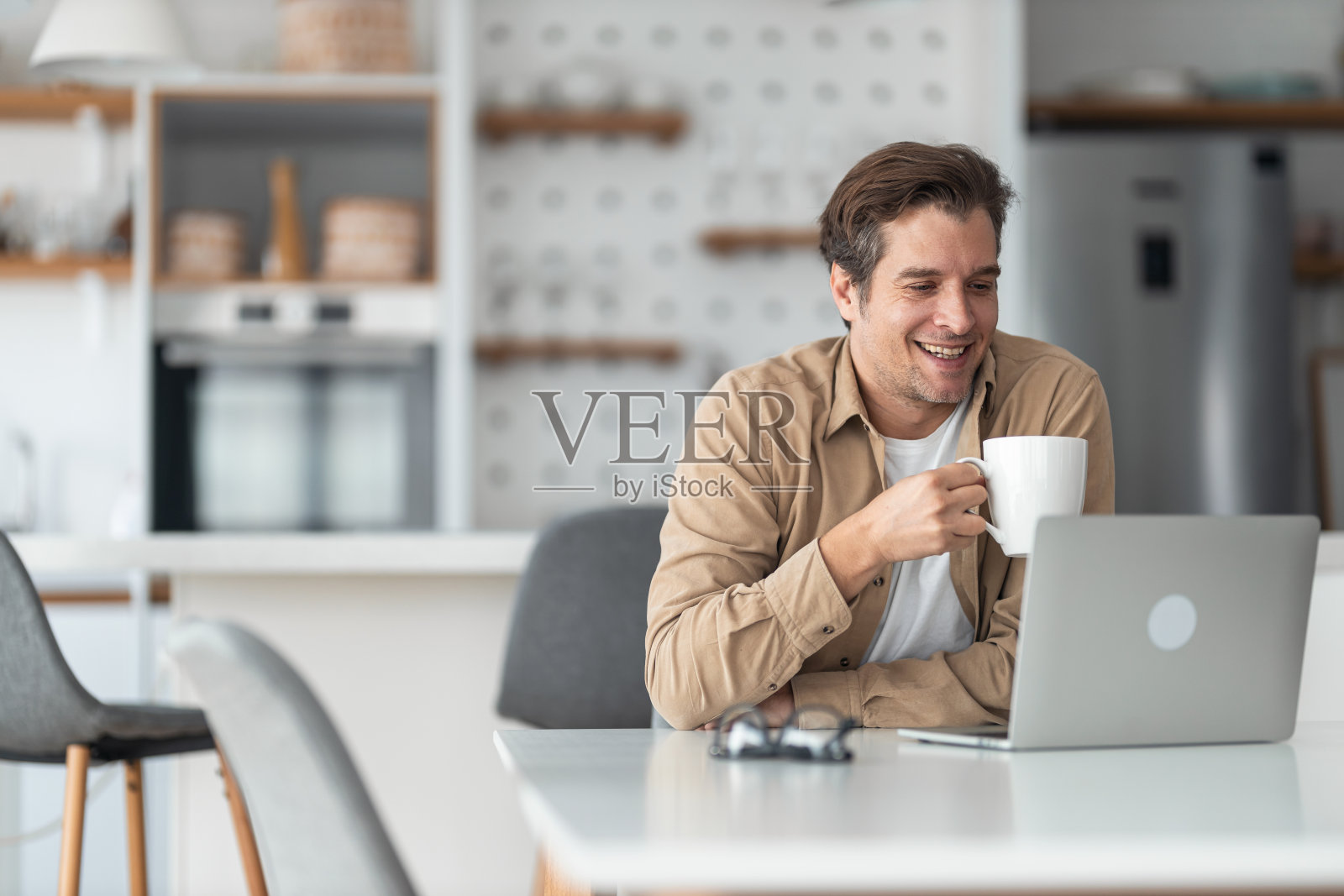 一名中年男子在清晨一边喝咖啡一边阅读电子邮件。照片摄影图片