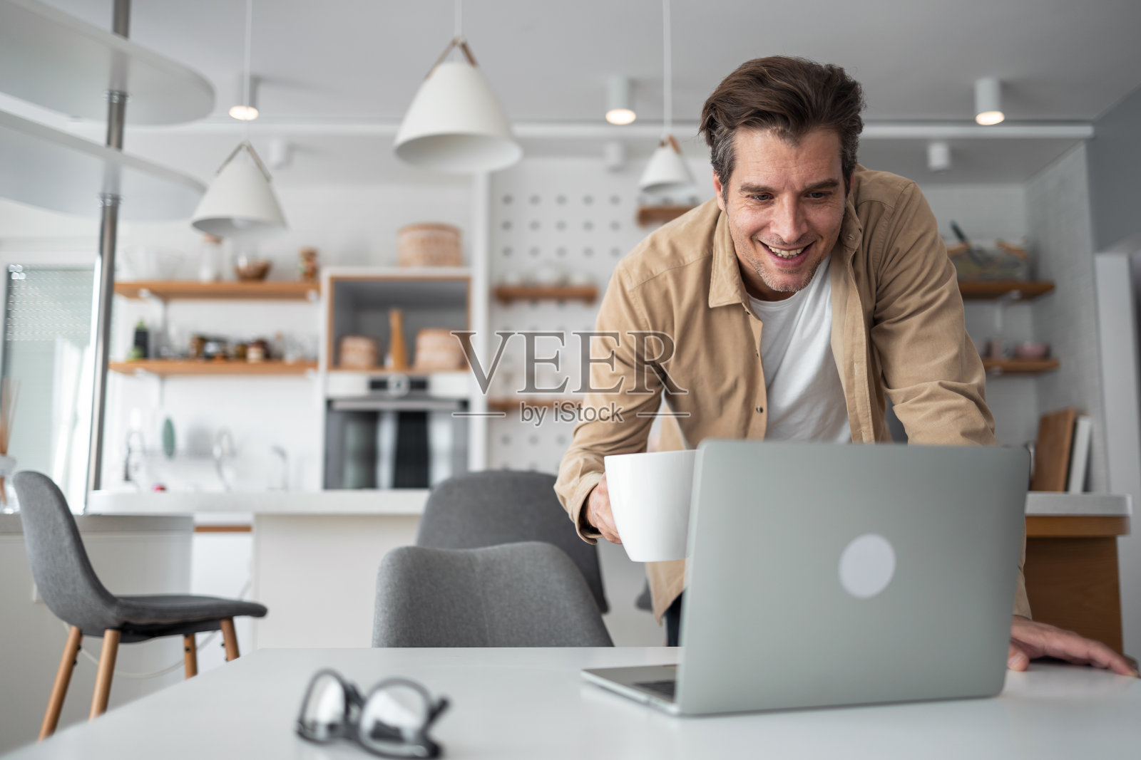 中年男子看起来很满意他在笔记本电脑屏幕上看到的东西。照片摄影图片