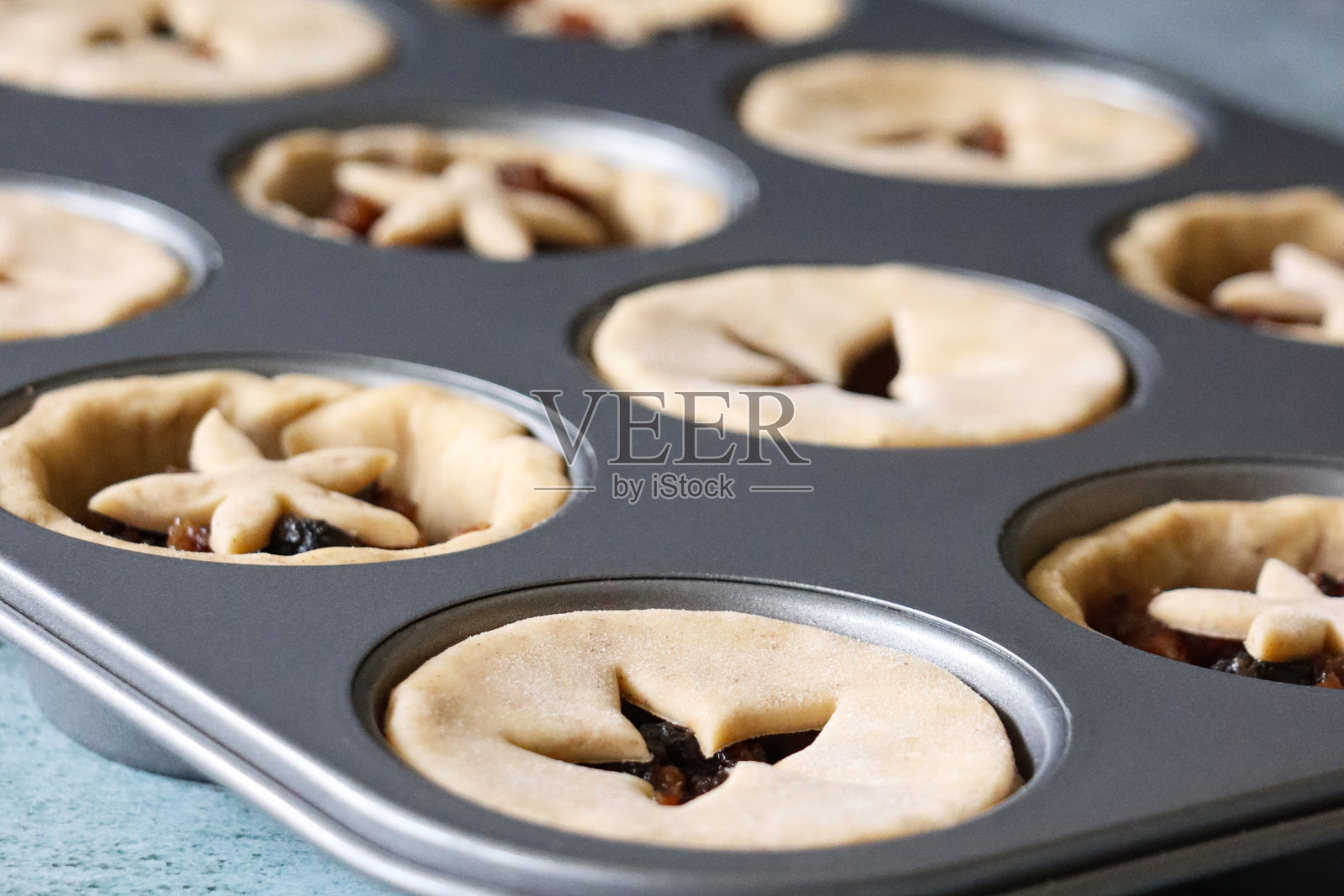 松饼盘是一排排生的、自制的肉馅饼，上面盖着糕点星形精细的盖子，节日的圣诞甜点酥皮糕点，上面有甜的肉碎(切碎的干果、蒸馏酒和香料)，突出的重点是前景照片摄影图片