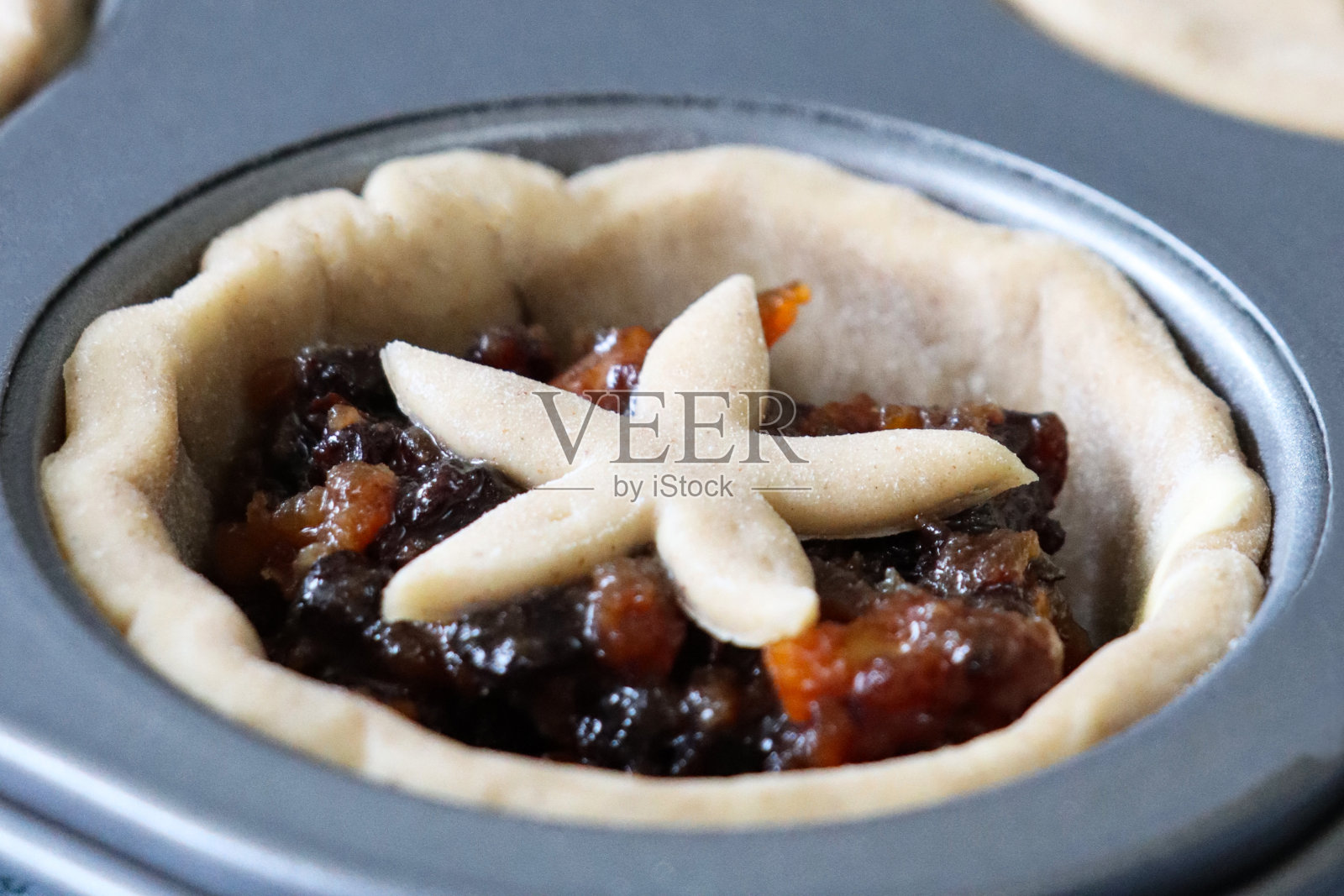 全帧图像松饼托盘个人生，自制的肉馅饼顶部有糕点星星详细的盖子，节日圣诞甜点酥皮糕点甜肉馅(切碎的干果，蒸馏酒，香料)，提高焦点前景照片摄影图片