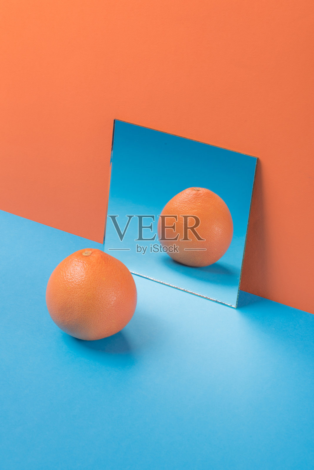 橘色背景下蓝色桌子上的葡萄柚照片摄影图片