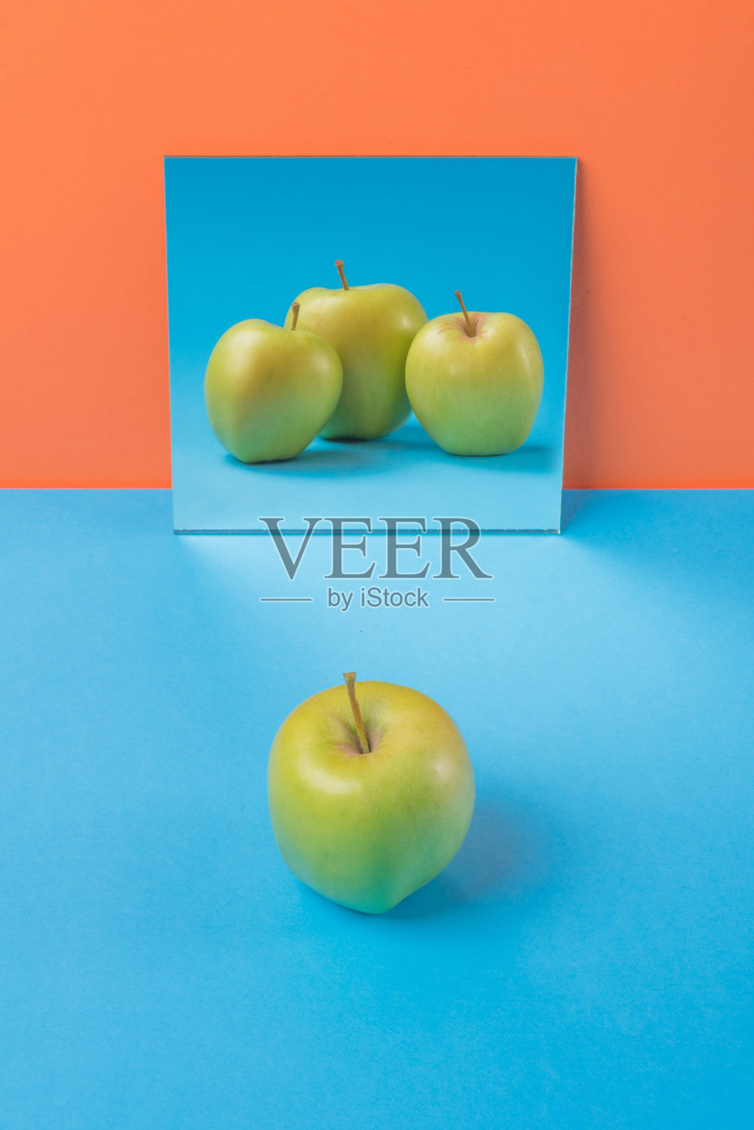 苹果在蓝色的桌子孤立在橙色的背景上照片摄影图片