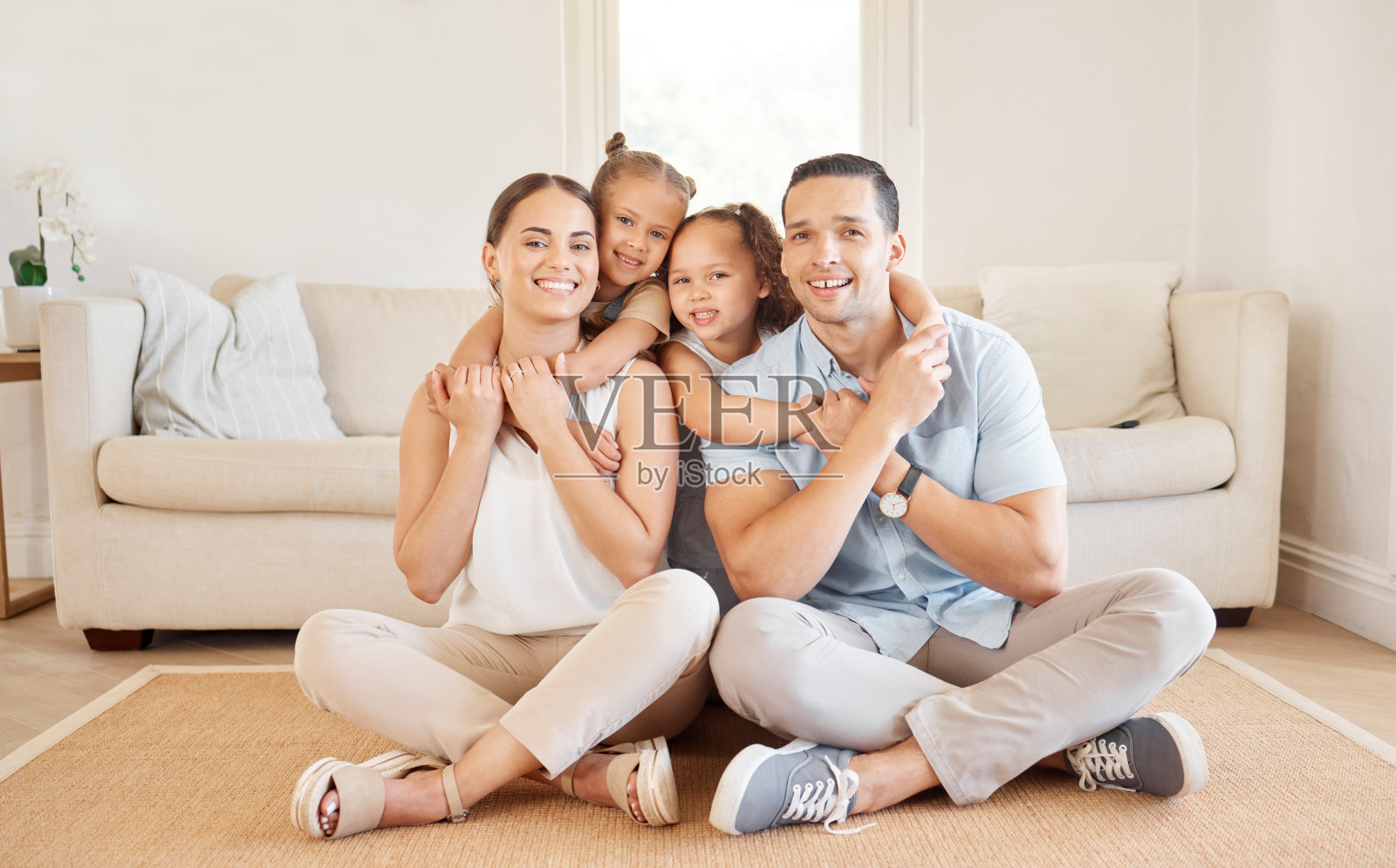 这张照片拍摄的是一对年轻夫妇和他们的两个年幼的女儿在家里的亲密关系照片摄影图片