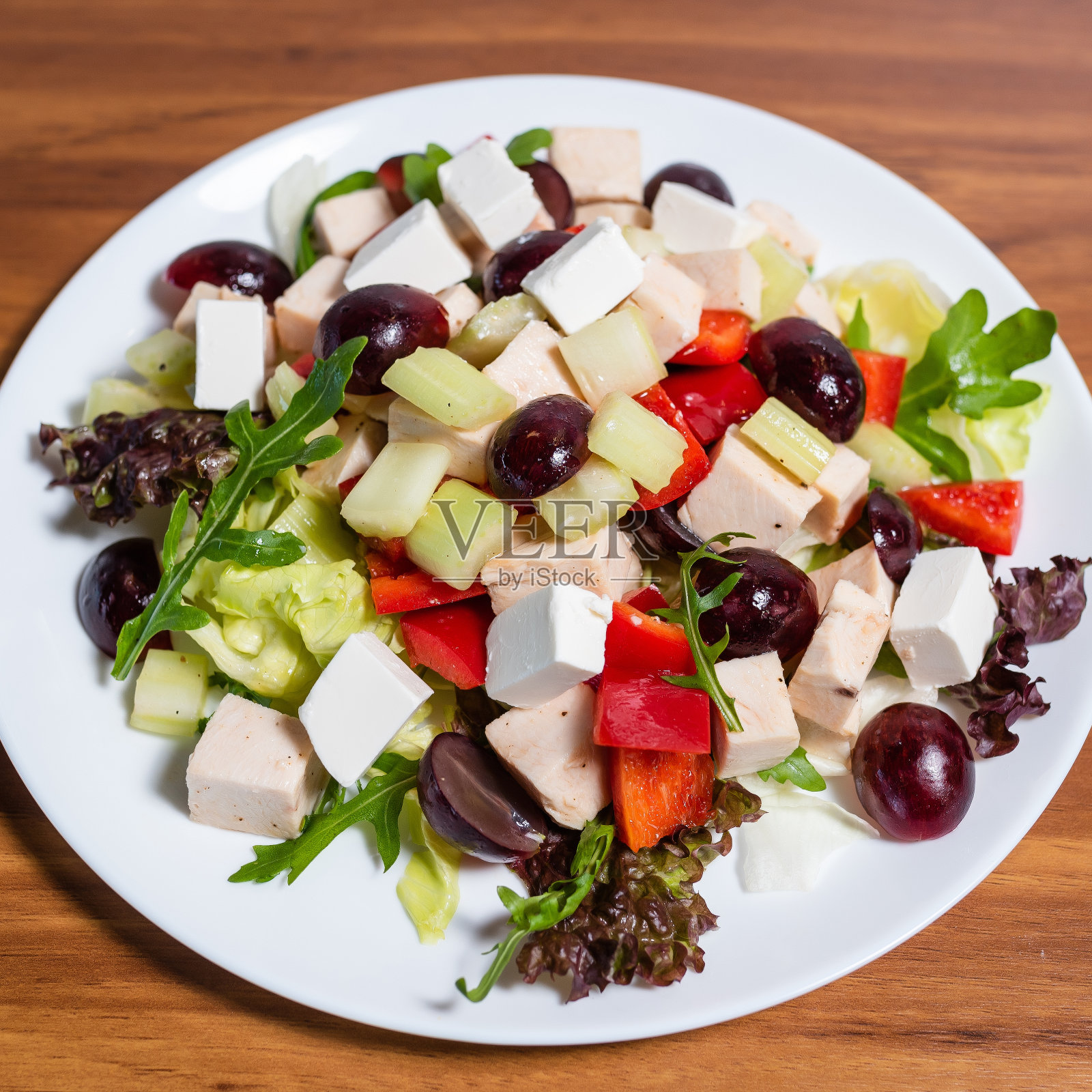 木桌上的新鲜蔬菜沙拉配羊乳酪、芝麻菜、生菜和葡萄照片摄影图片