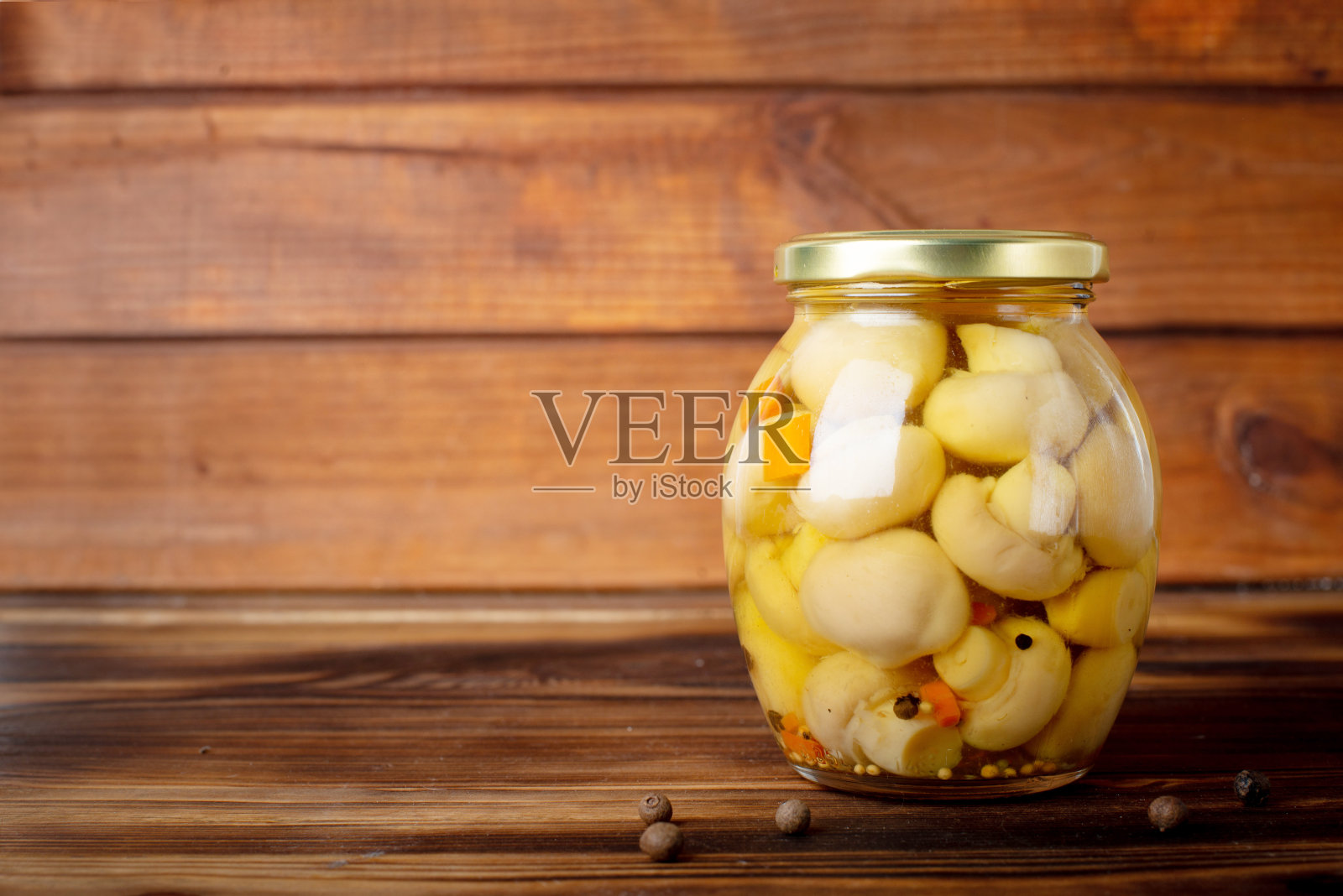 将腌蘑菇放入碗中，加入香料和香草。在木制背景上。照片摄影图片