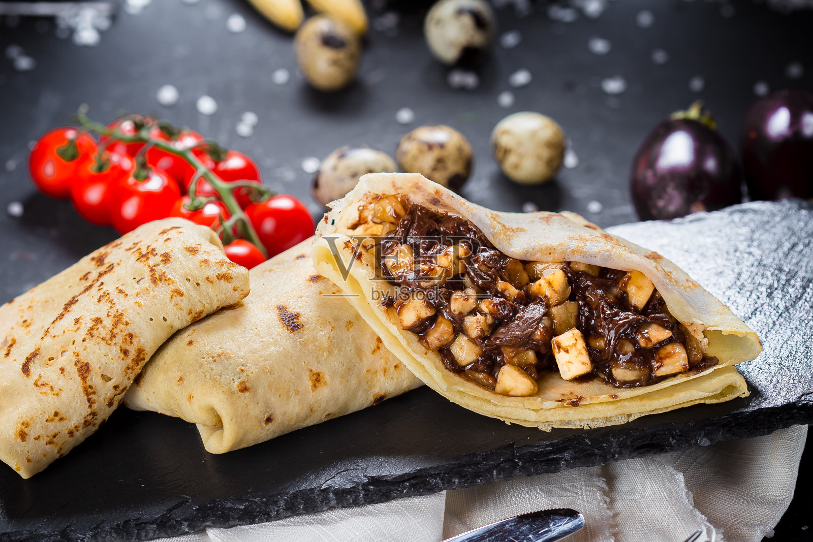 在一个盘子上，煎饼与巧克力酱和苹果片，樱桃番茄，刀具在一个黑色孤立的背景，特写，顶部照片摄影图片