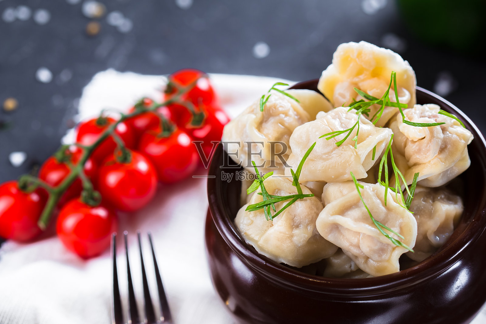 盘子上放着香草饺子，圣女果，黑色孤立背景的餐具，特写，顶部照片摄影图片