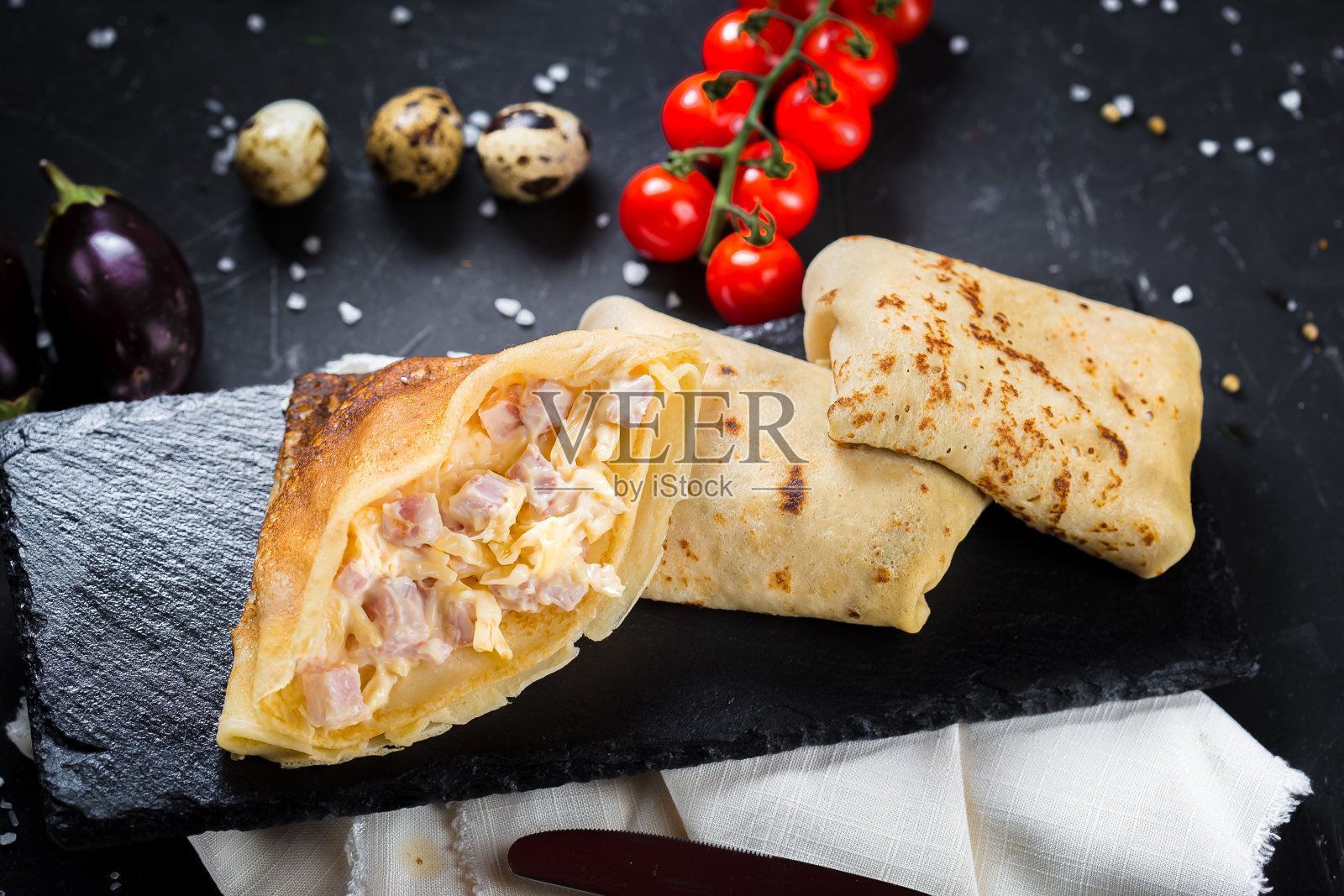 盘子上是煎饼配奶酪和火腿片，圣女果，黑色孤立背景上的餐具，特写，顶部照片摄影图片