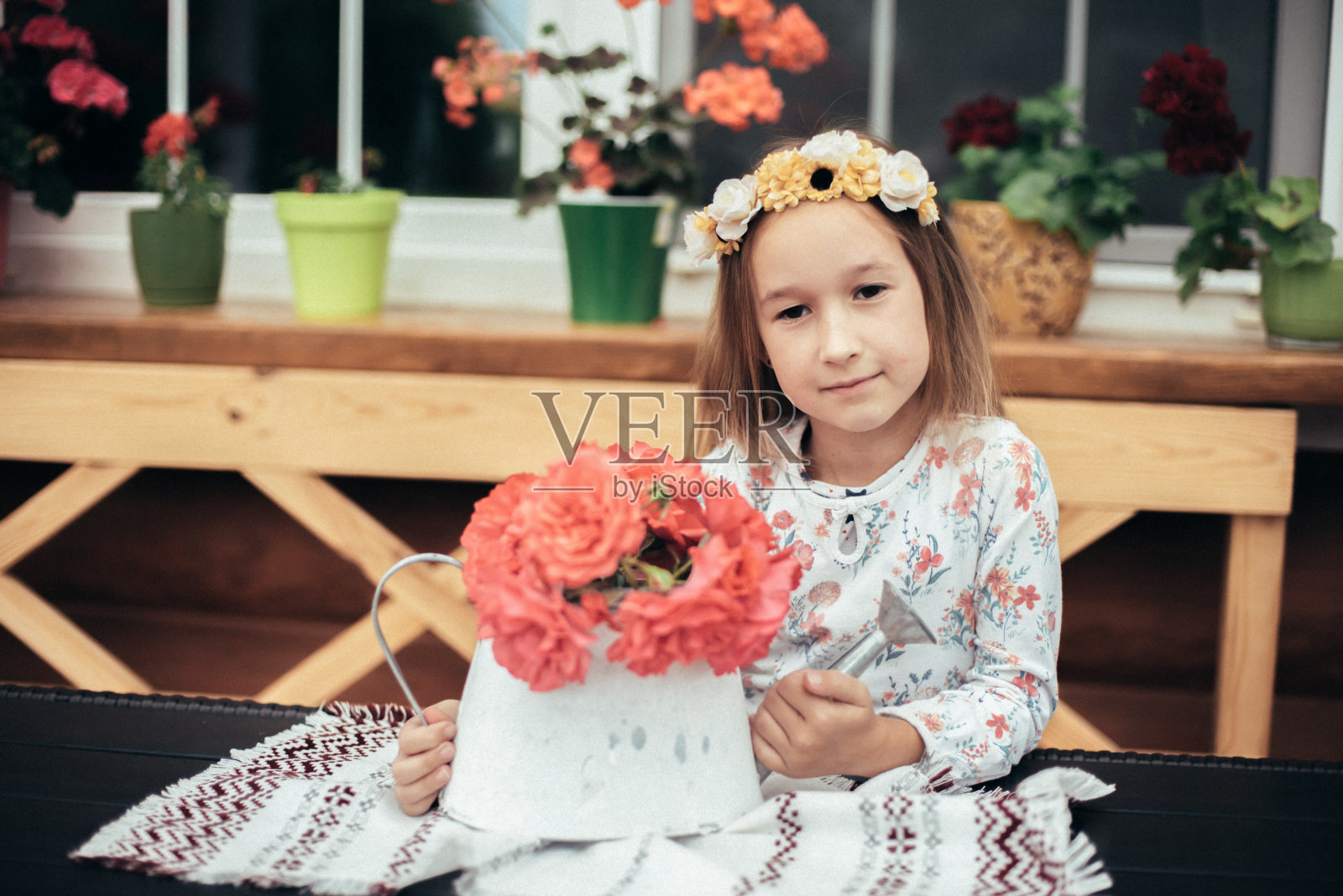 一个手里捧着一束粉红色花，头上戴着花环的孩子。照片摄影图片