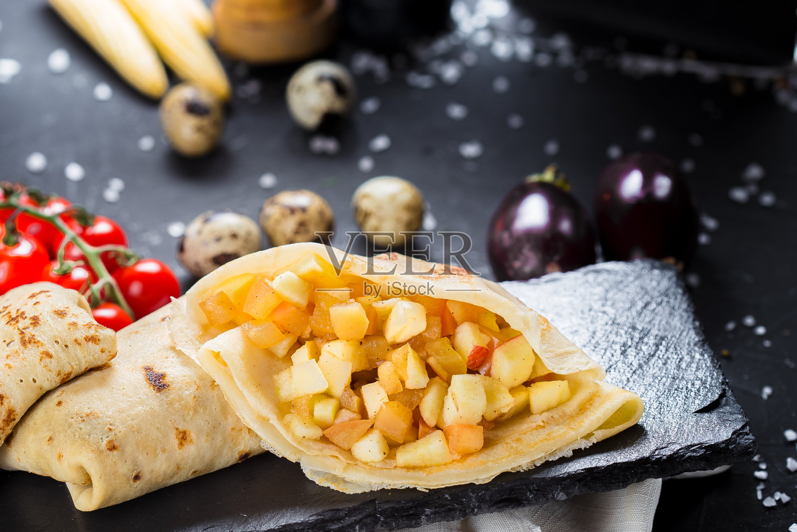 在一个盘子上，煎饼与苹果和水果，樱桃番茄，刀具在一个黑色的孤立背景，特写，顶部照片摄影图片