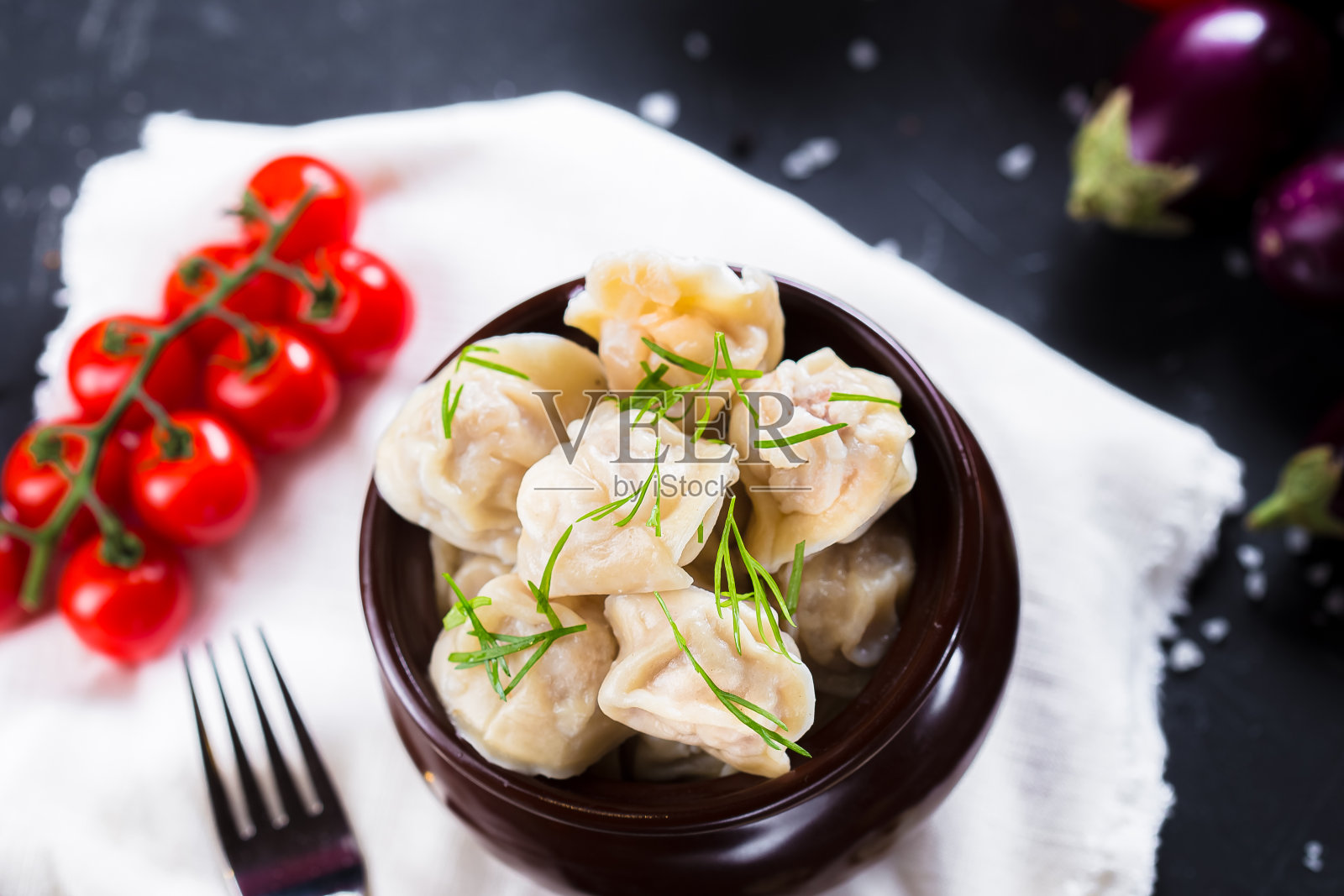 盘子上放着香草饺子，圣女果，黑色孤立背景的餐具，特写，顶部照片摄影图片