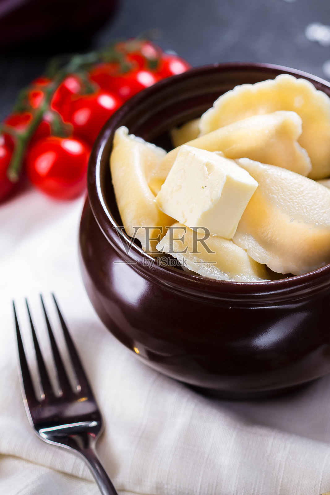 盘子上的饺子配黄油，圣女果，餐具在黑色孤立的背景上，特写，顶部照片摄影图片