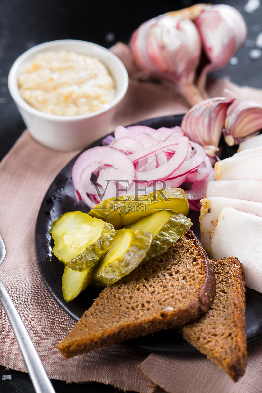 在一盘冷开胃酒，新鲜培根片，煮土豆，洋葱圈和黑面包，樱桃番茄，刀具上一个黑色孤立的背景，顶部照片摄影图片