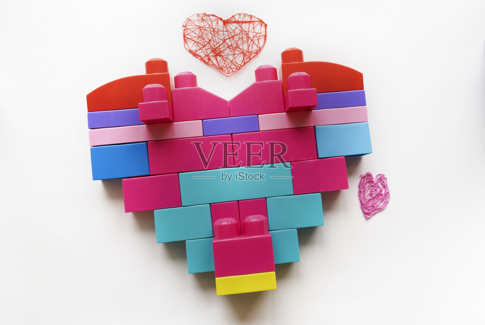 在白色的背景上，一个大型构造器的粉红色细节做成的心形。情人节贺卡。孩子爱他的母亲照片摄影图片