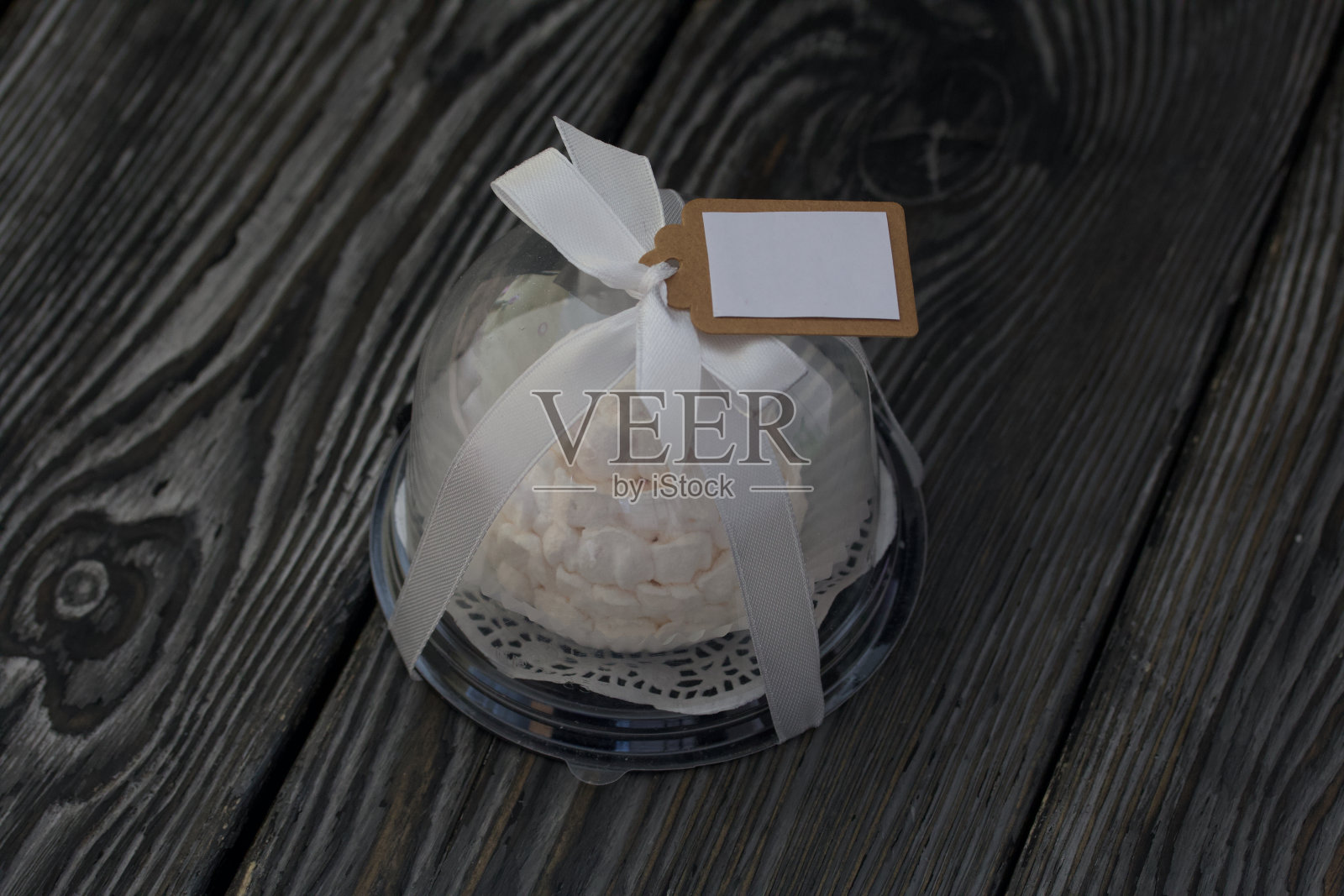 透明烧瓶中的棉花糖球果。用丝带系在蝴蝶结上。松木板。照片摄影图片