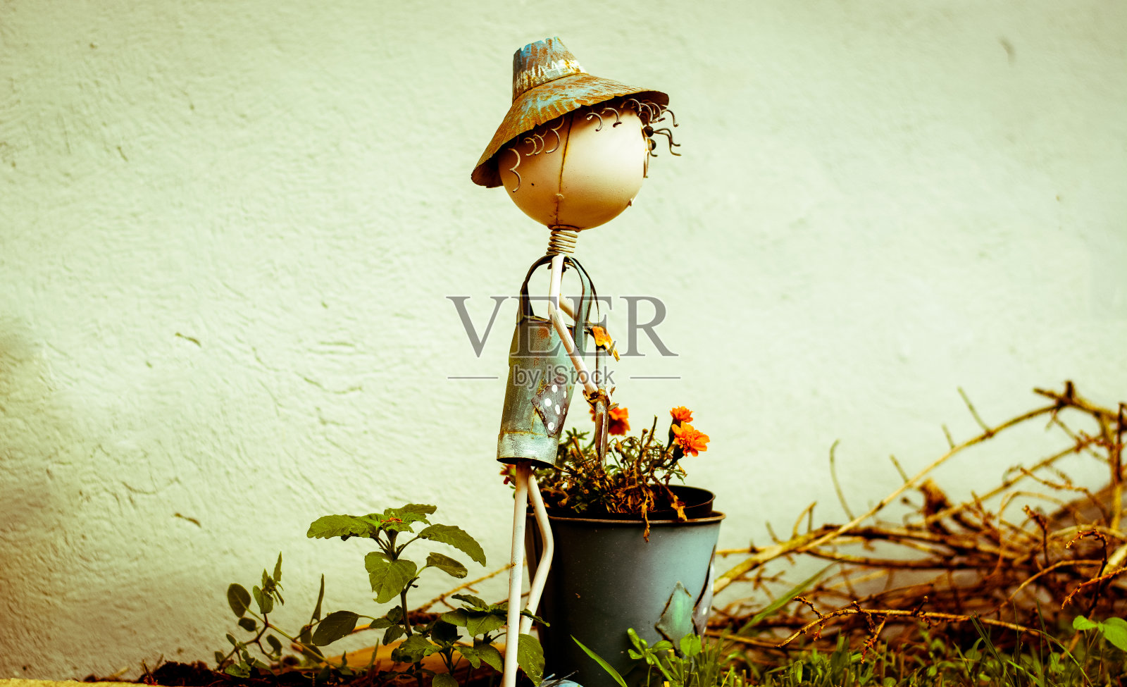 一个拿着装满鲜花的小金属娃娃照片摄影图片