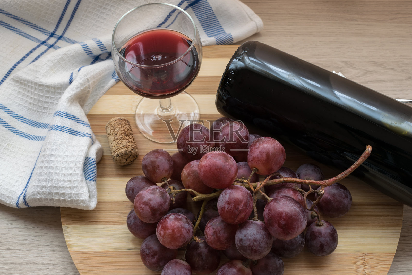 一杯红酒，一串葡萄和一瓶木制背景的葡萄酒照片摄影图片
