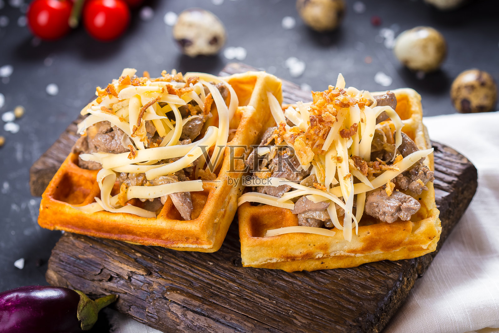 一个木制的厨房砧板上放着比利时华夫饼、奶酪和肉、圣女果和餐具，背景是黑色的孤立，特写，顶部照片摄影图片