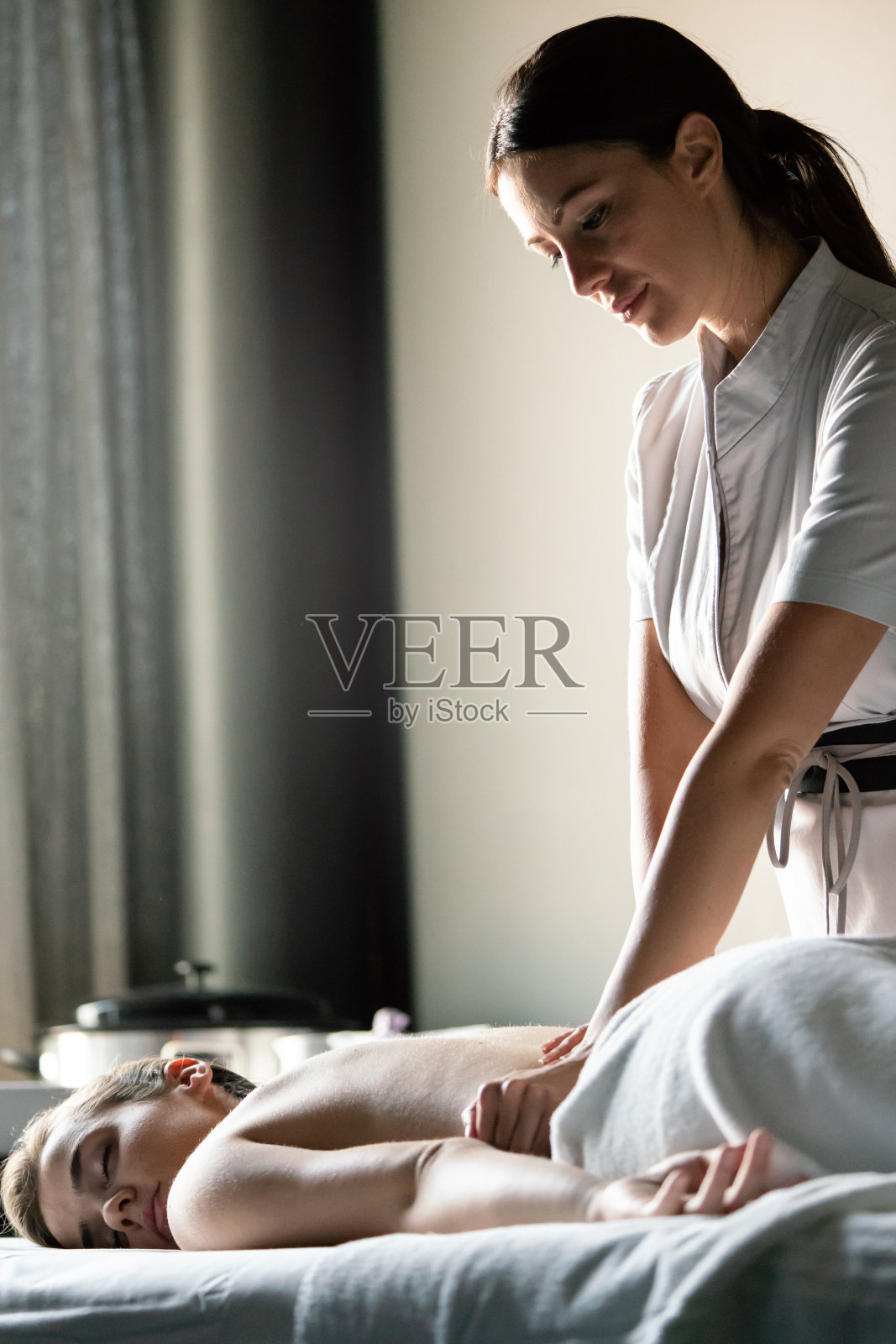 美丽的年轻女子得到水疗按摩治疗在美容水疗沙龙照片摄影图片