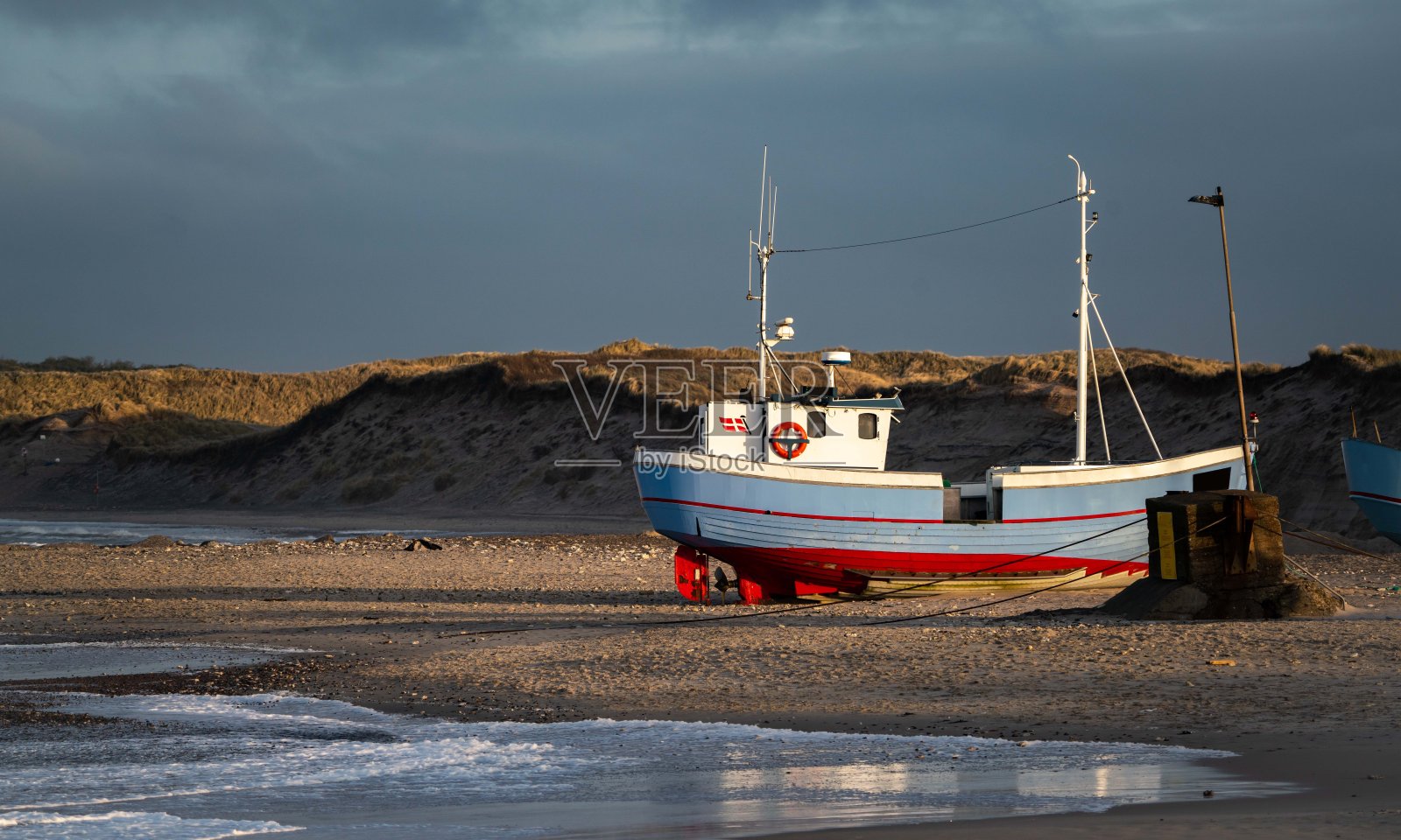 在一个暴风雨的日子里，丹麦北部norre vorupor海滩上的传统渔船照片摄影图片
