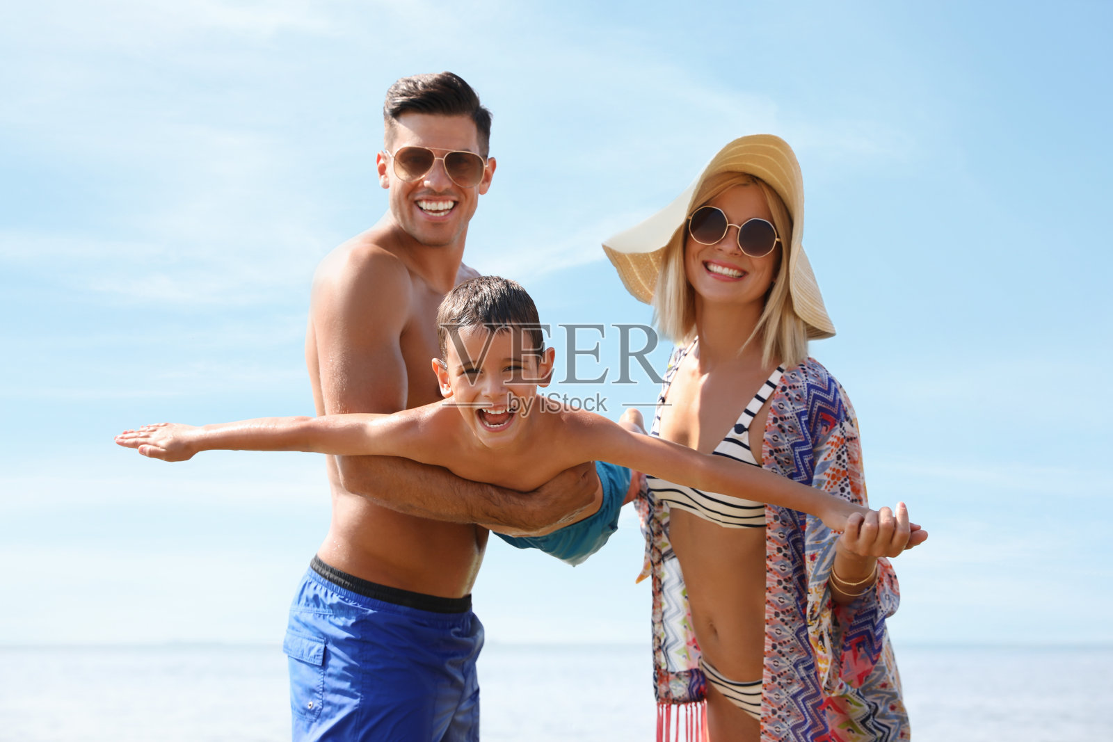 父母在沙滩上和儿子玩耍。家庭度假照片摄影图片