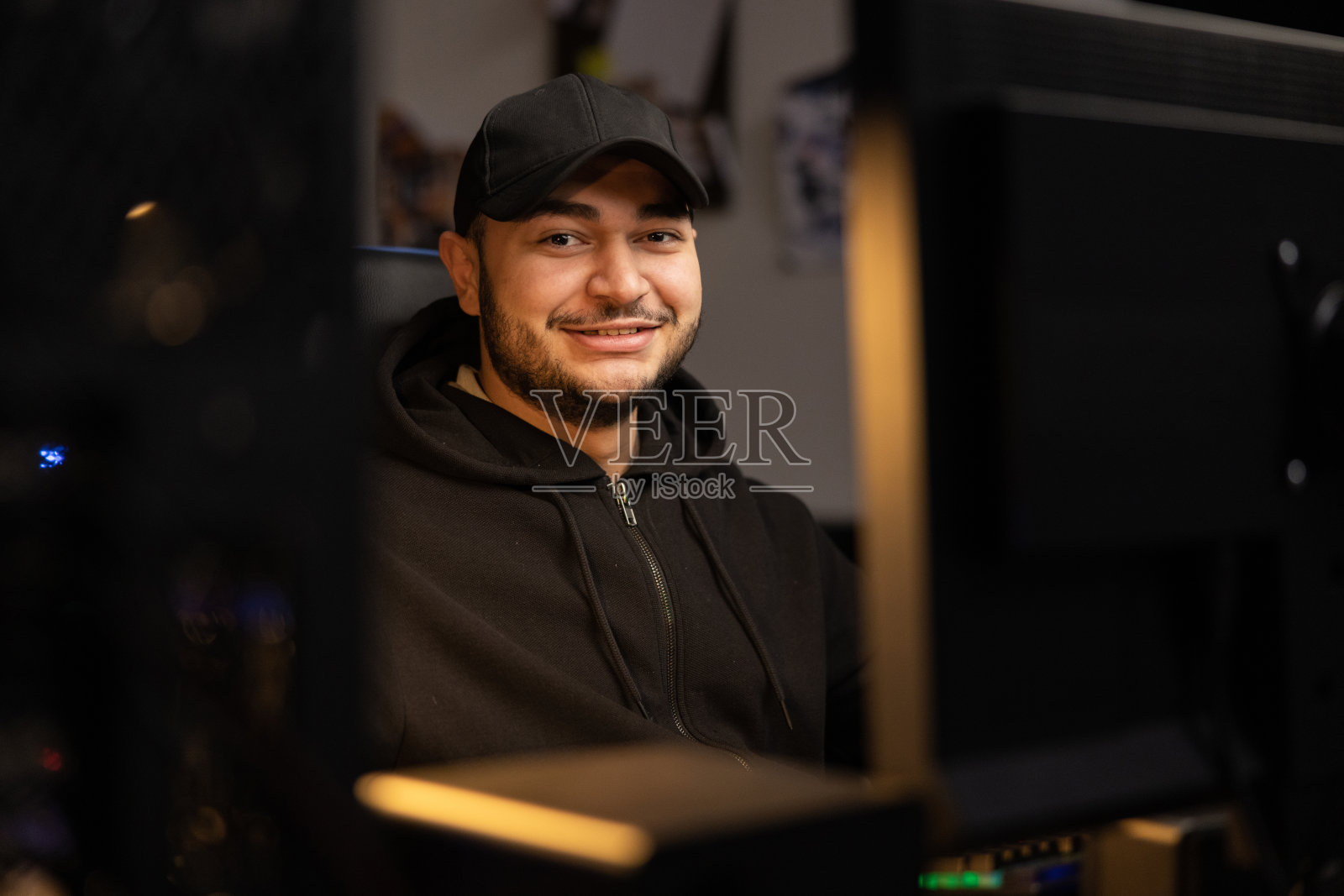 这是一个留着胡子、穿着黑色衣服、带帽运动衫的男人的肖像，他在IT行业远程工作，他是程序员、计算机科学家、数据库开发人员照片摄影图片