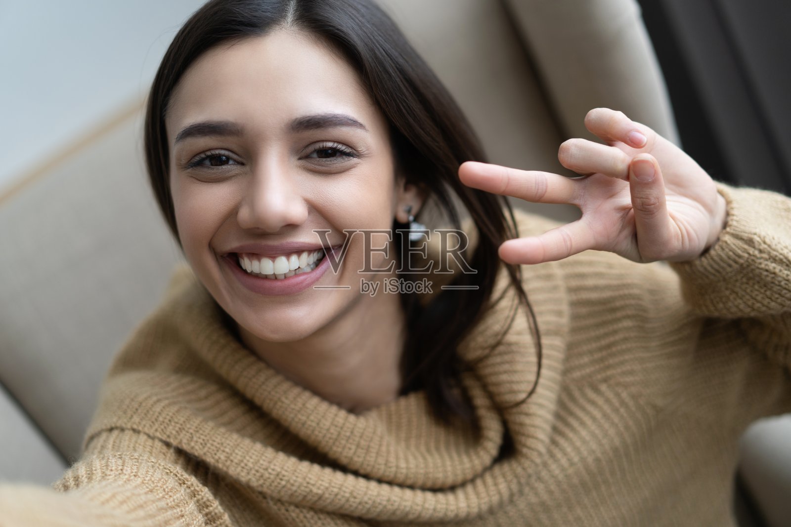 照片特写，时尚的20岁的女人微笑着看着相机，在客厅里拍自拍照。照片摄影图片