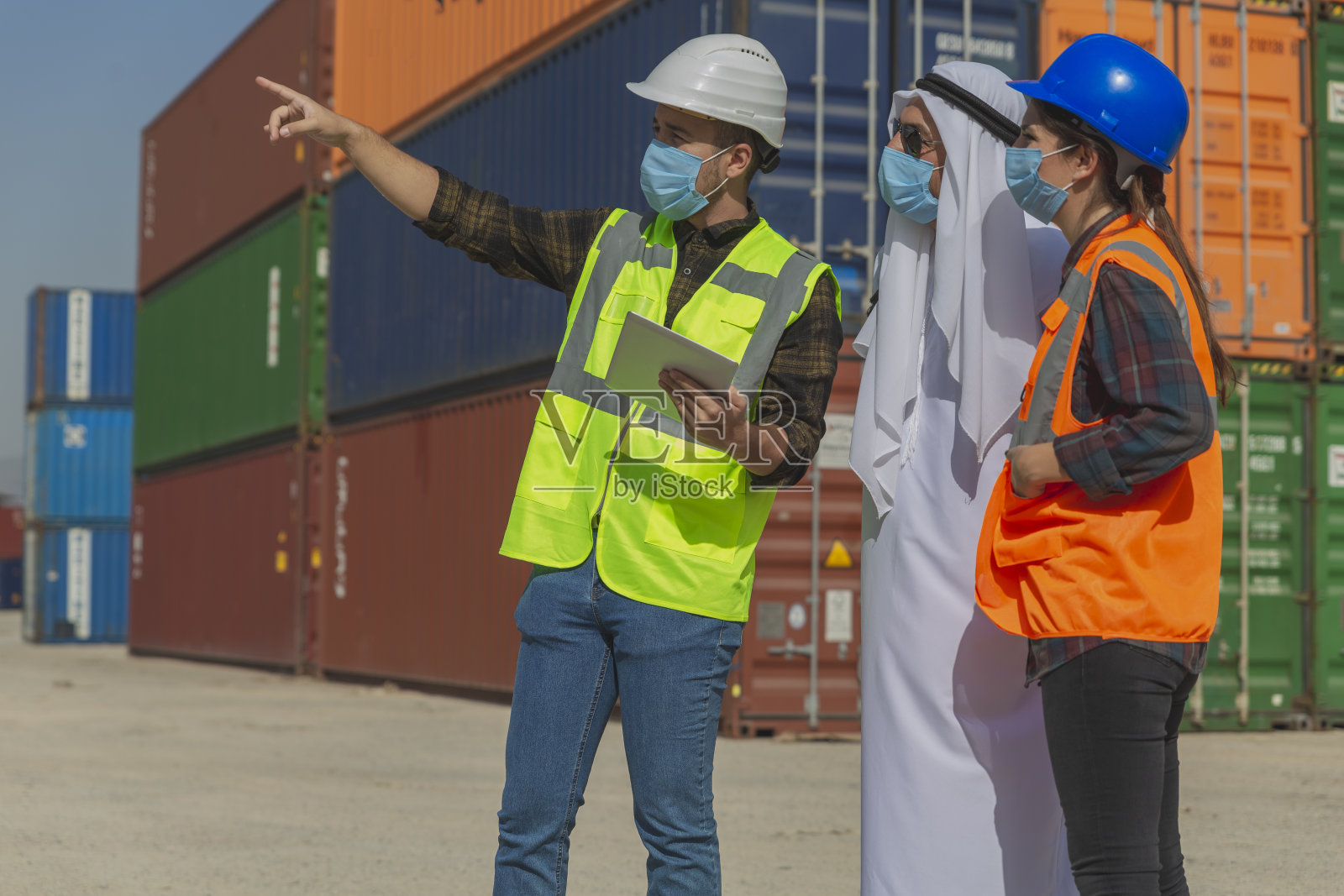 疫情期间，戴着口罩的中东商人和工程师在一个大型商业码头外工作照片摄影图片