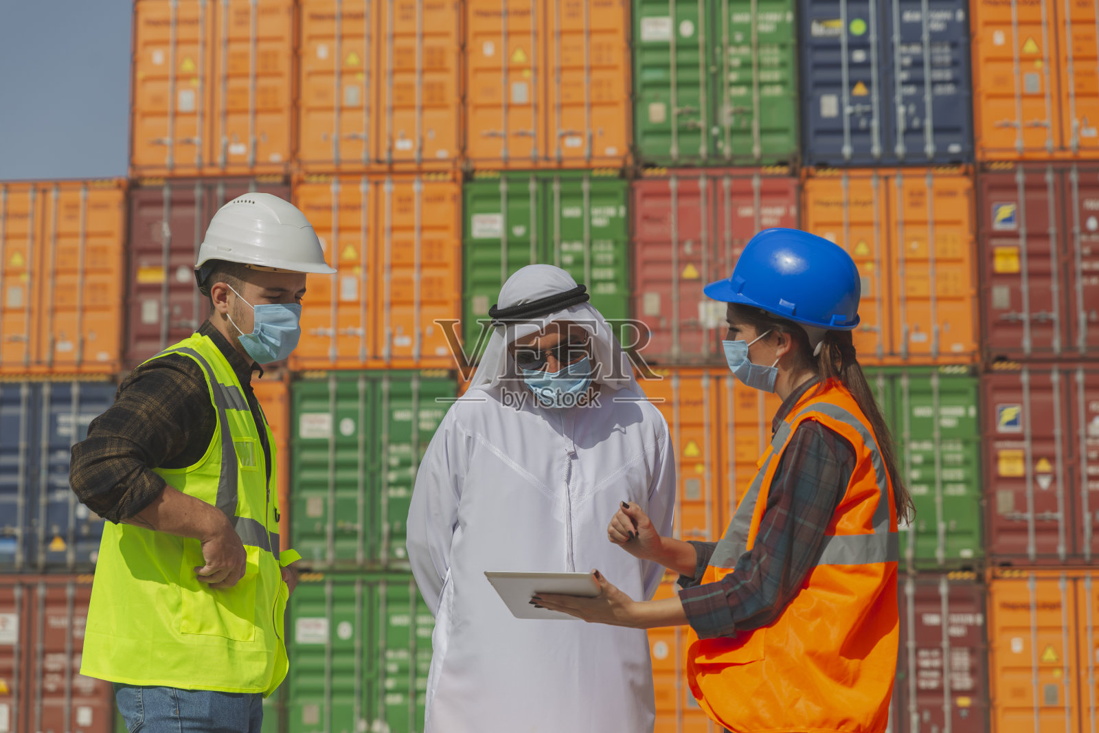 疫情期间，戴着口罩的中东商人和工程师在一个大型商业码头外工作照片摄影图片
