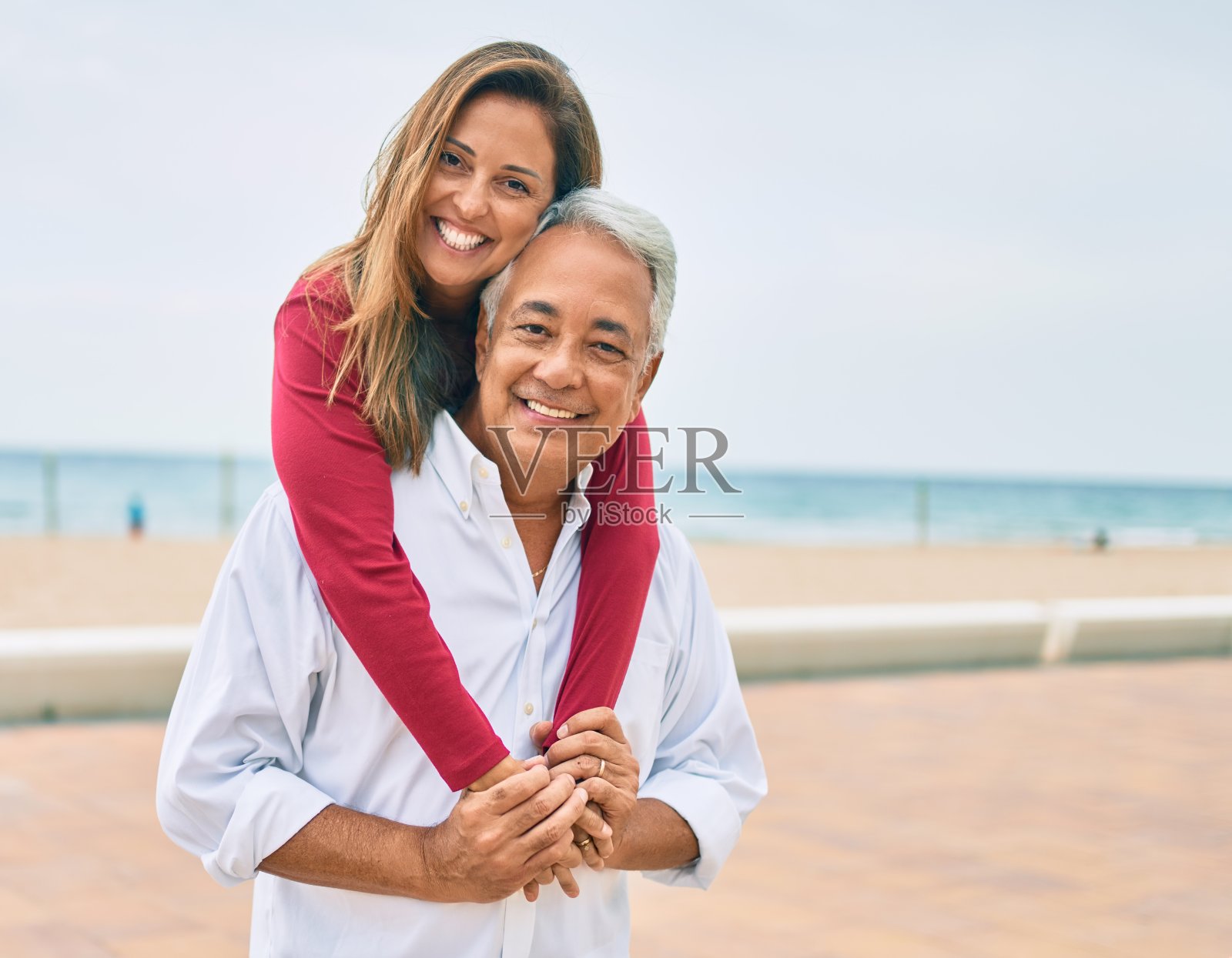 一对中年西班牙夫妇幸福地微笑着，拥抱着走在街上。照片摄影图片