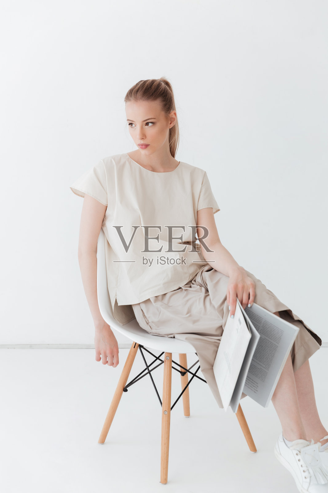 专心的金发女士坐在室内看书。照片摄影图片