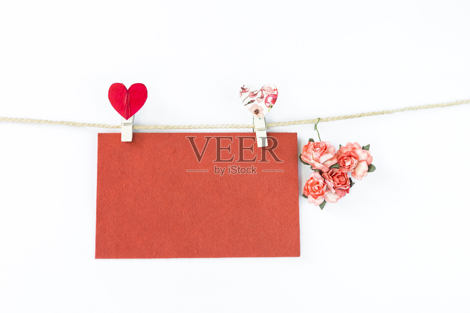 空白红纸卡片，带心形夹和玫瑰纸花在绳子上照片摄影图片