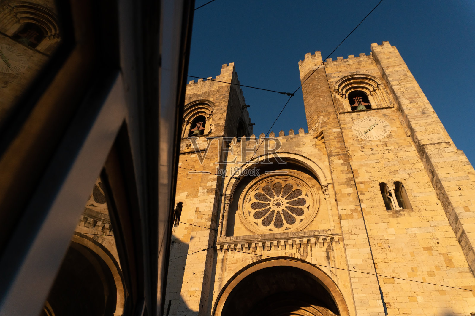 日落时分，里斯本大教堂的窗户映照着历史悠久的有轨电车。葡萄牙照片摄影图片