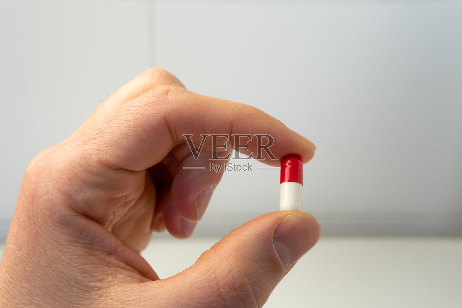 一个男人手里拿着一颗背景模糊的药丸。照片摄影图片