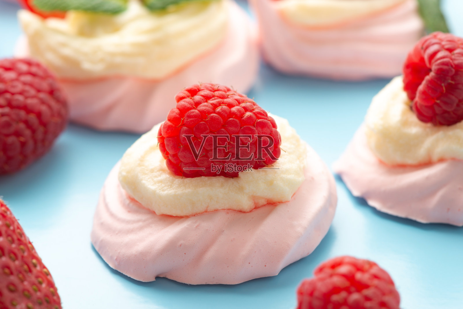 用新鲜的覆盆子装饰在蓝色背景上的巴甫洛娃蛋白蛋糕照片摄影图片